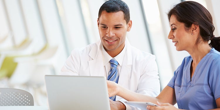 Two physicians look at a laptop